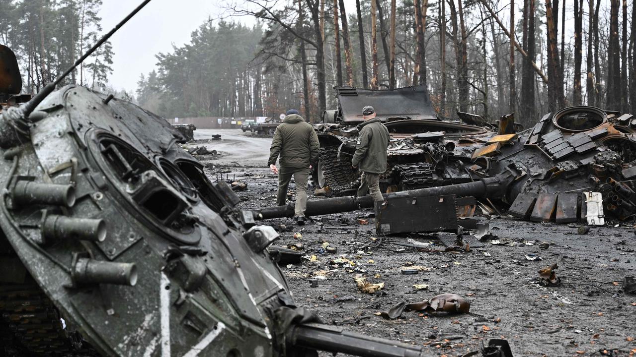 Ukrainian servicemen walk next to destroyed Russian tanks and armoured personnel carriers in Dmytrivka village, west of Kyiv. Photo by Genya SAVILOV / AFP