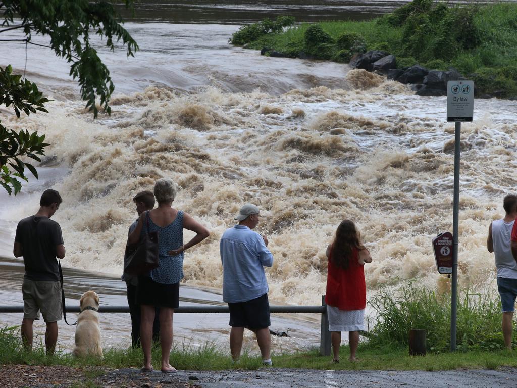 People gather to watch floodwaters in the Coomera River spill over the Oxenford Weir. Picture Glenn Hampson