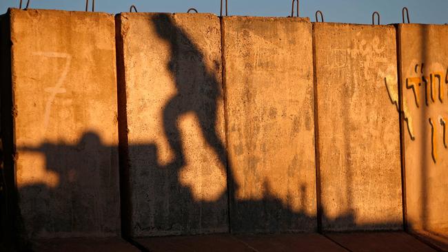 The shadow of an Israeli soldier climbing on a Merkava tank is seen on barricades along the northern border with Lebanon near the Israeli settlement of Shtula. Picture: AFP