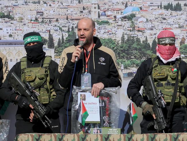 Hostages L to R: Israeli-American Sagui Dekel-Chen, Israeli-Argentinian hostage Yair Horn and Israeli-Russian Sasha Trupanov stand on stage next to Palestinian militatns during their handover over to a Red Cross team in Khan Yunis in the southern Gaza Strip on February 15, 2025, as part of the sixth hostage-prisoner exchange. Masked Hamas militants handed over three Israeli hostages to the Red Cross in Gaza on February 15, in the sixth hostage-prisoner swap under its ceasefire agreement with Israel, an AFP journalist reported. (Photo by Eyad BABA / AFP)