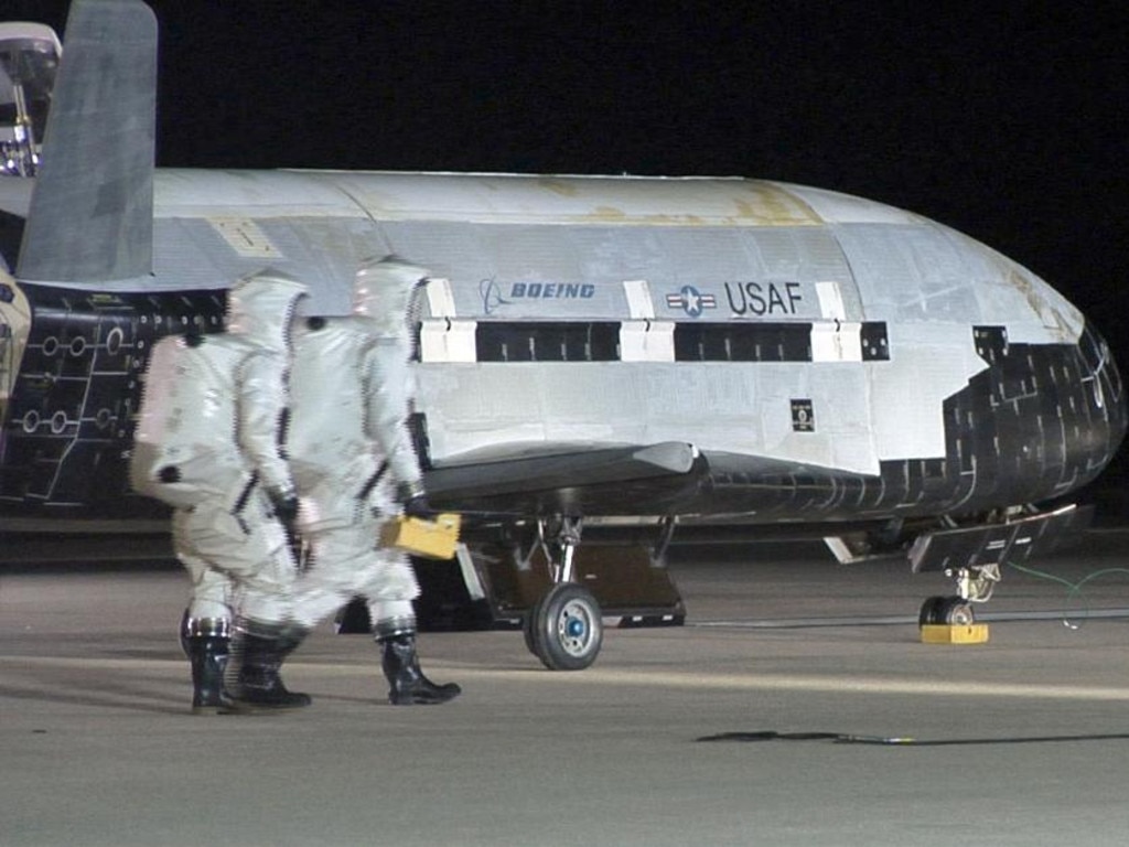An X-37B is approached by ground personnel after spending more than a year in orbit. What the reusable space-plane does up there is anybody’s guess.