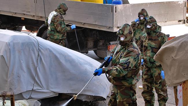 Iraqi health officials and Civil Defence staff wearing protective suits spray disinfectant in the commercial markets, in downtown and hotels used by Iranian citizens in Najaf, Iraq. Picture: AP