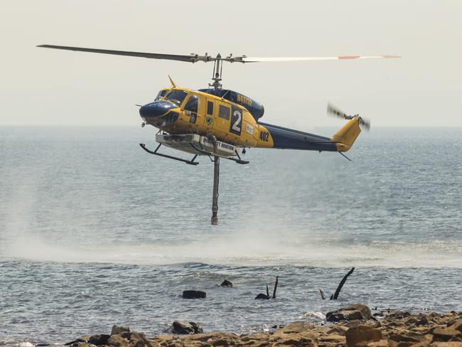 A water-bombing helicopter fills up as part of the firefighting effort at Miena. Picture: Heath Holden/Getty