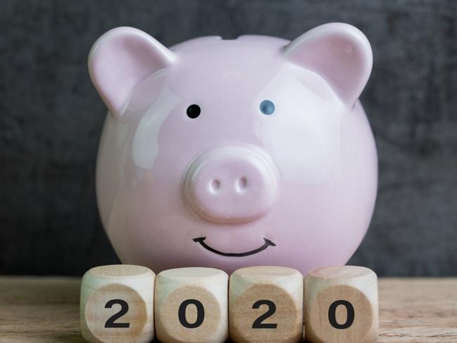 Year 2020 financial goal, budget or investment, happy smiling pink piggy bank with wooden cube block with number 2020 on table and dark black background stock photo