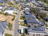 Aerial view of houses and streets in new wealthy suburb in Adelaide foothills with construction in foreground and coastline in background: large houses, landscaped gardens, rooftop solar systems,