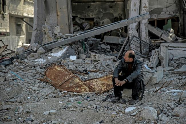 A Palestinian man sits amid the rubble of a building destroyed during Israeli strikes in Gaza City