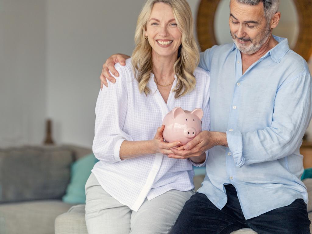 Mature Couple holding a piggy bank in their new home. Home savings concept. Both are happy and smiling. money generic