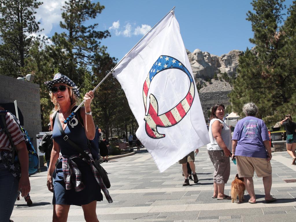 A Donald Trump supporter holding a QAnon flag visits Mount Rushmore National Monument. Picture: Scott Olson/Getty Images/AFP