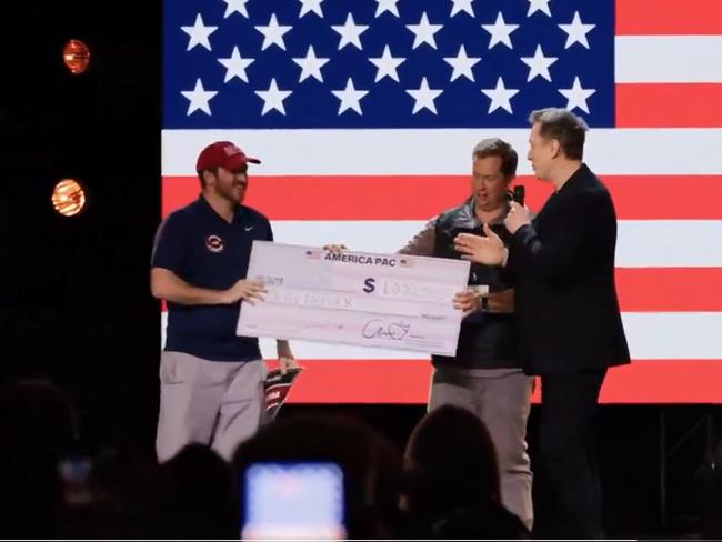 Elon Musk hands over a cheque to John Dreher. Picture: X