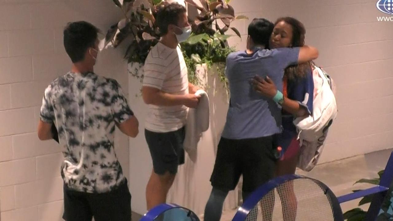 Naomi Osaka is hugged by her team members after her loss to Amanda Anisimova.