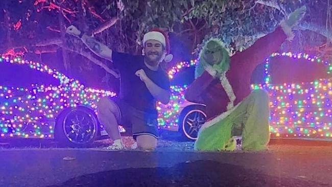 Hayden McIntyre and the Grinch pose in front of their festive vehicles