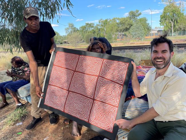 NT Arts Minister Chansey Paech displays a painting by Pintupi artist Thomas Japaltjarri with members of his family. Picture -  Supplied