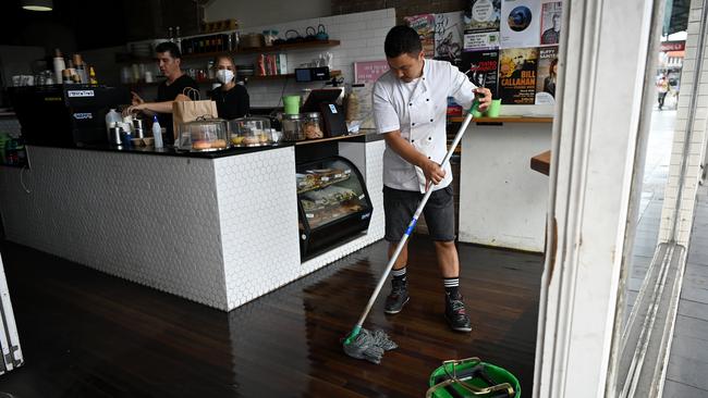 A worker mops the floor at a cafe on King Street in Newtown in Sydney. Picture: AAP.