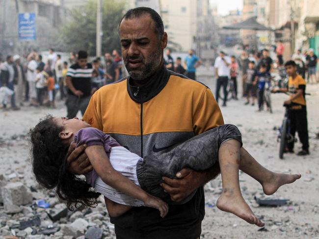 A Palestinian man carries an injured a girl following an Israeli strike, in Khan Yunis in the southern Gaza Strip on October 14. Picture: AFP