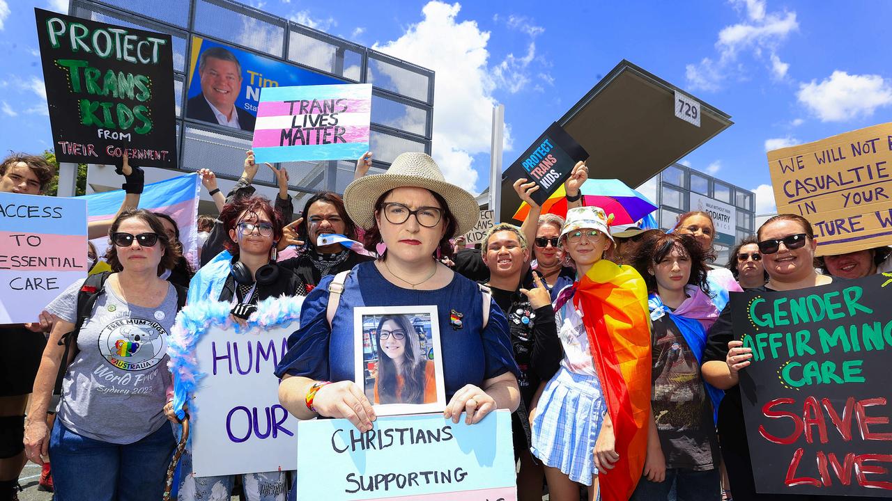 Sarah Rae with a picture of her daughter Diana join protesters at Tim Nicholls Electorate office in a gathering to protest the decision to stop puberty blockers. Picture: Adam Head