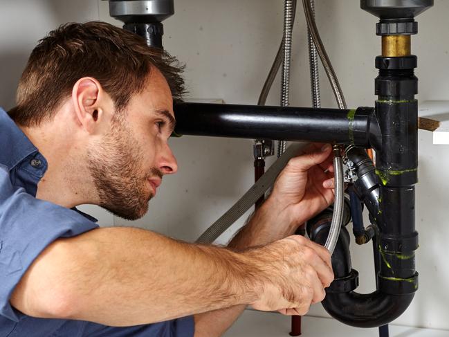 Plumber with tools doing reparation in the kitchen.