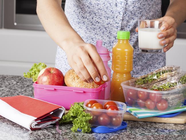 Young mother preparing healthy and tasty lunch box for child