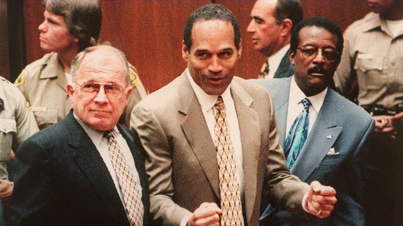 Defendant O.J. Simpson (C) cheers while standing with his attorneys F. Lee Bailey (L) and Johnnie Cochan Jr (R), after hearing his not guilty verdict. (Photo by Agence France Presse/Getty Images)