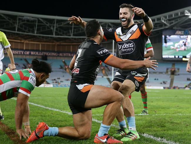 David Nofoaluma of the Tigers celebrates scoring a try with teammate James Tedesco.