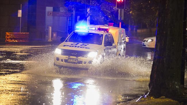 A police vehicle with lights flashing negotiates flooding at the intersection of Eddy and Pitt streets in Sydney's CBD overnight. Picture: Chris McKeen