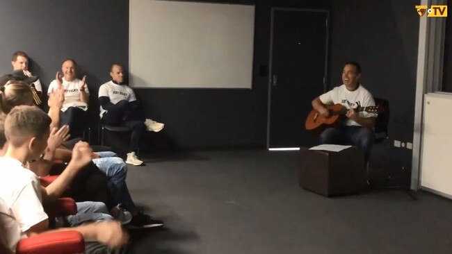 Alastair Clarkson sings while playing the guitar in front of the Hawthorn players. Picture: hawthornfc.com.au (screenshot)