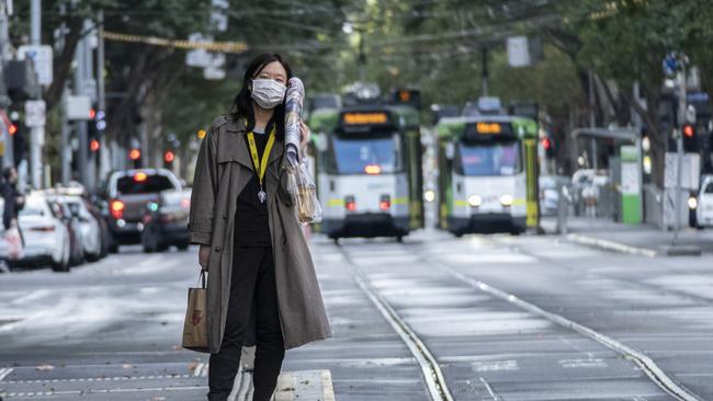 A woman weaing a mask waits for a tram in Melbourne. Picture: Getty Images