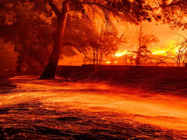 TOPSHOT - Embers whip across the ground as homes burn during the Eaton fire in Pasadena, California on January 7, 2025. A ferocious wildfire in a Los Angeles suburb devoured buildings and sparked panicked evacuations January 7, as hurricane-force winds tore through the region. More than 200 acres (80 hectares) was burning in Pacific Palisades, a upscale spot with multi-million dollar homes in the Santa Monica Mountains. Across town, on the northern edge of Los Angeles, another fire broke out in Eaton Canyon, near Pasadena, quickly consuming 200 acres (81 hectares) later in the night, according to Angeles National Forest officials. (Photo by JOSH EDELSON / AFP)