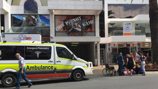 A woman receives medical attention after riding her electric hire bike straight into a barrier and garden on Orchid Avenue, Surfers Paradise.