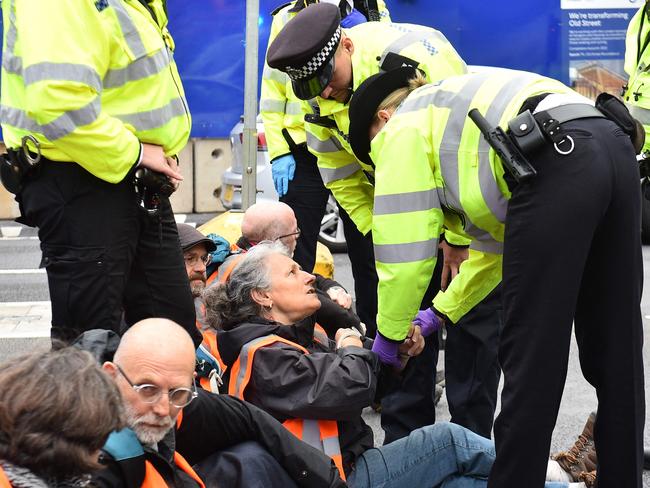 Climate activists from the group Insulate Britain block the road as police officers work to remove and arrest them during a demonstration calling for the UK government to fund the insulation of Britain's homes in central London on October 8, 2021. - Climate activist group Insulate Britain blocked roads in central London and the M25 motorway on October 8, 2021 in the latest action in their campaign to demand that the UK government funds a programme to insulate Britain's homes, starting with the homes of the poorest people in the country, amid a looming climate crisis. (Photo by Daniel SORABJI / AFP)