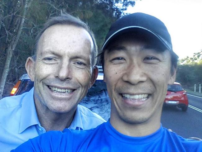 Former prime minister Tony Abbott poses for a selfie with soccer coach Roberto.