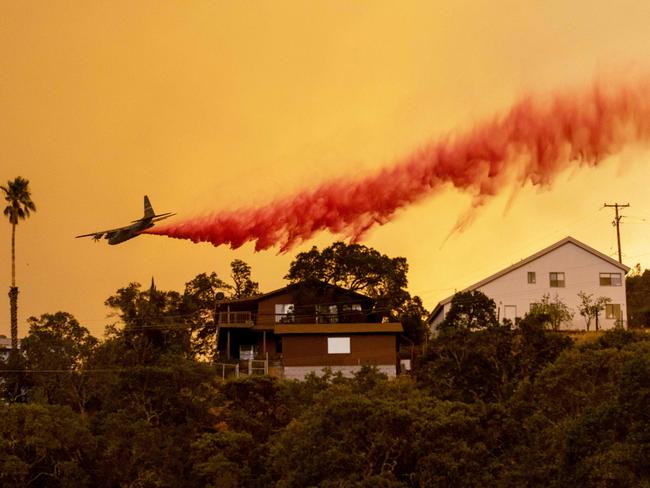 A flight drops fire retardant over homes in the Spanish Flat area of Napa, California as flames rage through. Picture: AFP