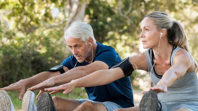 Couple stretching at park and listening to music.