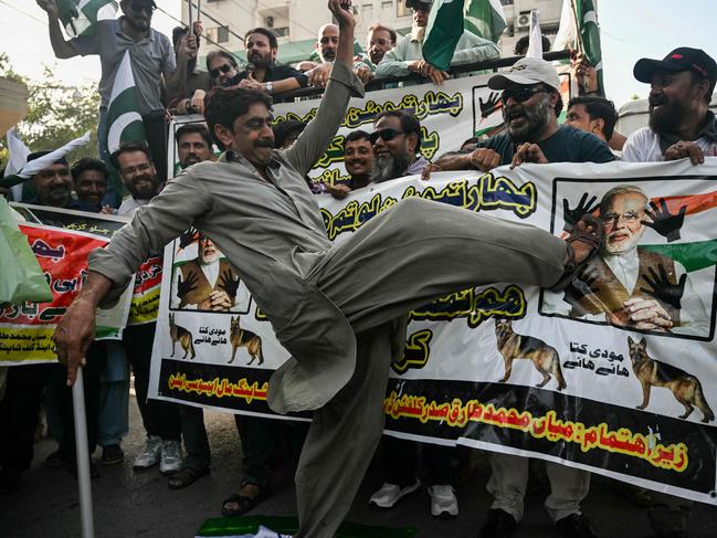 TOPSHOT - A trader kicking on the picture of Indiaâs Prime Minister Narendra Modi during an anti-India protest in Karachi on April 29, 2025. (Photo by Rizwan TABASSUM / AFP)
