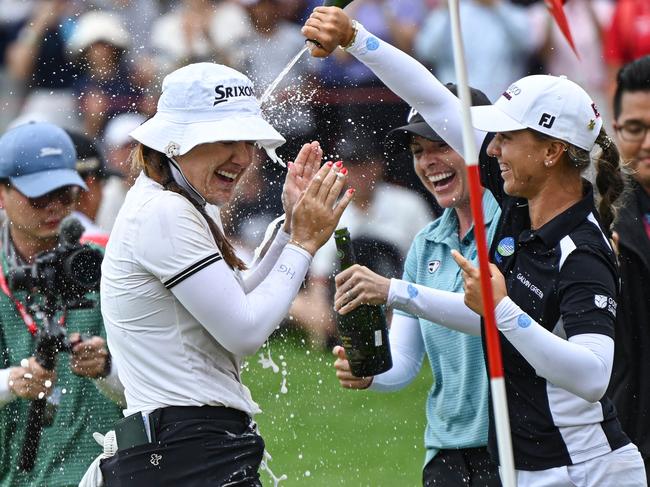 Hannah Green (L) of Australia celebrates with sparkling wine after winning the final round of the HSBC Women's World Championship golf tournament at Sentosa Golf Club in Singapore on March 3, 2024. (Photo by Roslan RAHMAN / AFP)