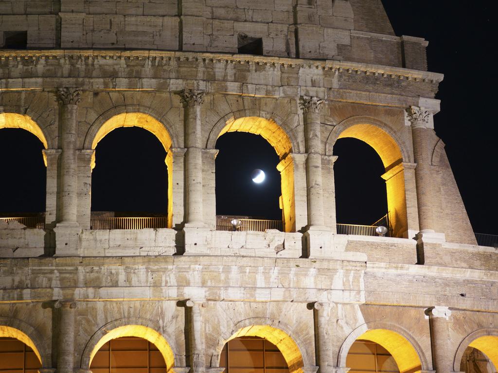 People watch at a rising full moon during a partial lunar eclipse, in Rome, late Tuesday, July 16, 2019. The eclipse coincides with the 50th anniversary of the launch, on July 16, 1969, of the Apollo 11 mission that took the first men on the moon. (AP Photo/Andrew Medichini)