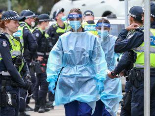 MELBOURNE, AUSTRALIA - JULY 05: Medical staff wearing PPE holding material about to walk into the Flemington Public housing flats on July 05, 2020 in Melbourne, Australia. Nine public housing estates have been placed into mandatory lockdown and two additional suburbs are under stay-at-home orders as authorities work to stop further COVID-19 outbreaks in Melbourne. The public housing towers will be in total lockdown for at least five days following a high number of positive coronavirus cases recorded in residents on those estates. The towers will be closed and contained, and the only people allowed in and out will be those providing essential services. Police will be placed on each floor of the towers and other police will control access points to the estates. Residents of 12 Melbourne hotspot postcodes are also on stay-at-home orders and are only able to leave home for exercise or work, to buy essential items including food or to access childcare and healthcare. Businesses and facilities in these lockdown areas are also restricted and cafes and restaurants can only open for takeaway and delivery.  (Photo by Asanka Ratnayake/Getty Images)