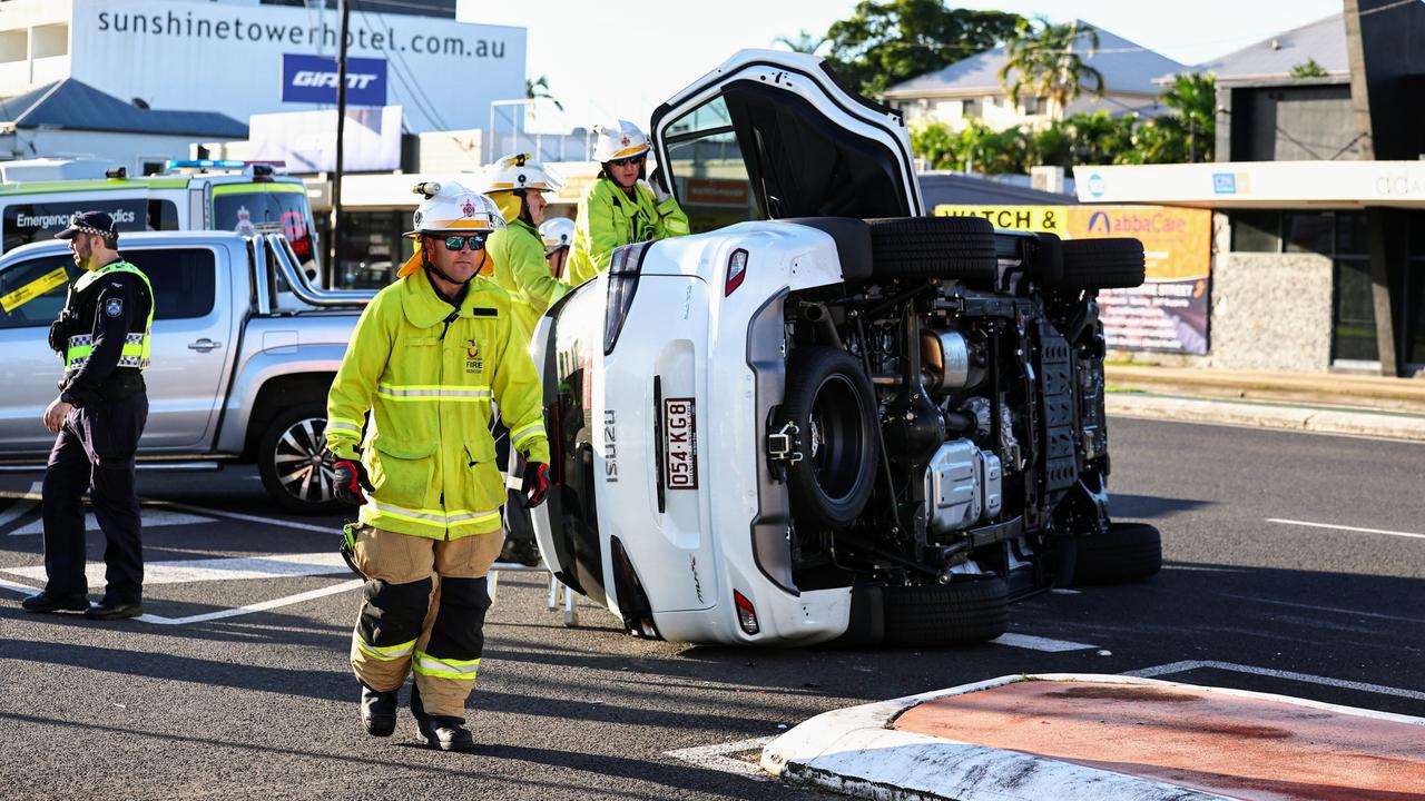 Queensland Fire and Emergency Services firefighters attend to the scene of a traffic collision between two utilities at the intersection of Sheridan and Minnie Streets, where one ute rolled onto its side. Picture: Brendan Radke