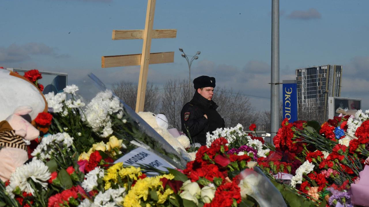 A police officer stands guard by a makeshift memorial in front of the burnt-out Crocus City Hall concert venue. (Photo by Olga MALTSEVA / AFP)