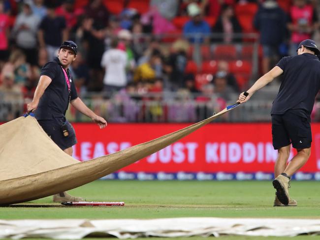 Groundsmen pull covers over the wicket during one of several rain delays.