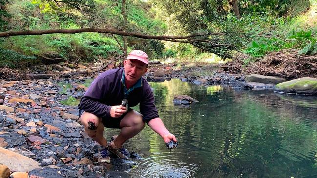 Dr Ian Wright with a handful of black sludge in Camp Gully Creek. Picture: Supplied