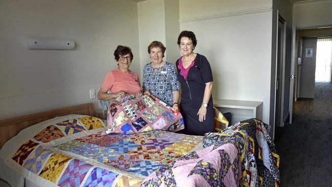 WELCOMING: Placing quilts for the opening of the Ozcare Toowoomba aged-care facility in Greenwattle St are (from left) Toowoomba Quilter Club members Fay Suley and Lee Hicks with facility manager Elizabeth Klein. Picture: Bev Lacey