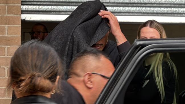 Junior Amone leaving Wollongong police station on Monday under the cover of his father’s jacket. Picture: Dylan Arvela