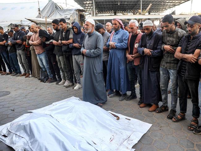 Mourners pray before the bodies of workers of the United Nations Relief and Works Agency for Palestine Refugees (UNRWA) at the Aqsa Martyrs' Hospital in Deir el-Balah in the centre of the Gaza Strip. They were killed when their truck was reportedly hit by bombardment. Picture: AFP