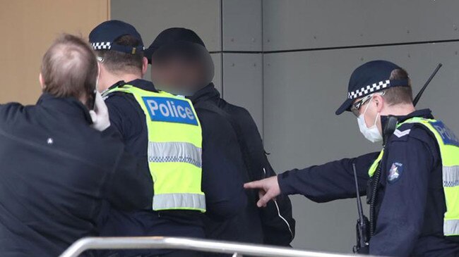 Police escort a man back into the building after he was spotted trying to leave one of the locked down Melbourne towers. Picture: David Grosling