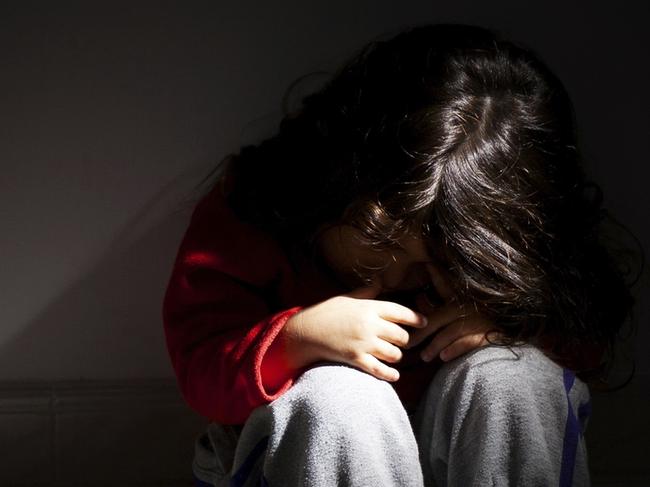 young girl sitting down alone in the dark. iStock image