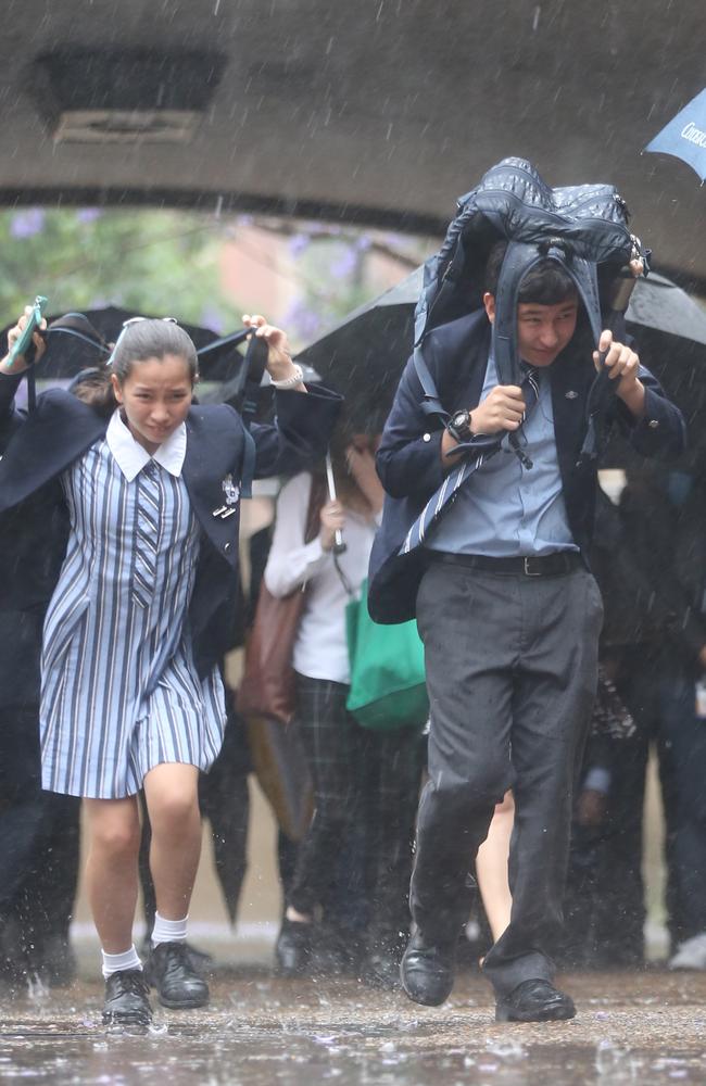 Students battle the weather on their way to school. Picture: John Grainger