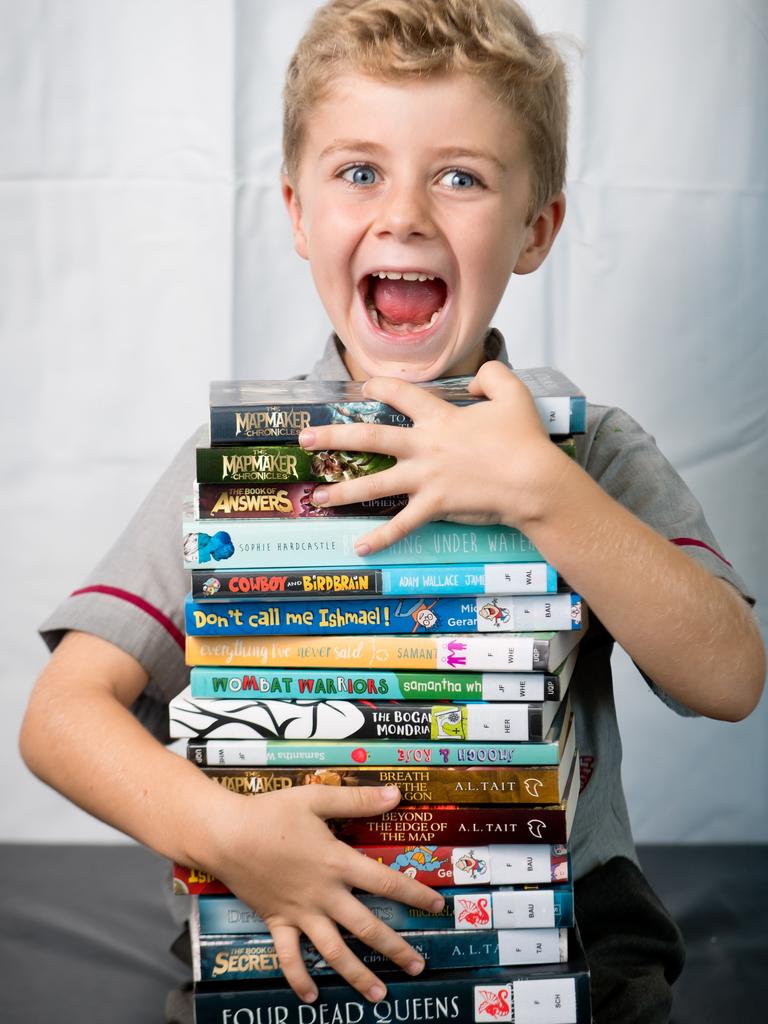 Elliot Ecklan, 6, with books by some of the authors appearing at the this year's Whitsunday Voices Youth Literature Festival.