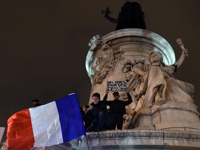 Liberty ... a black armband was placed on Lady Liberty at Place de la Republique as demonstrators for peace wave the French flag. Picture: AFP/Dominique Faget