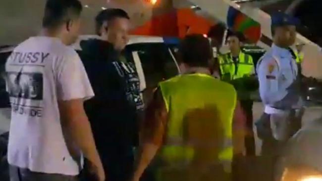 Stills from iPhone footage show men being removed by police after a Jetstar flight diverted to Bali. Picture: Supplied