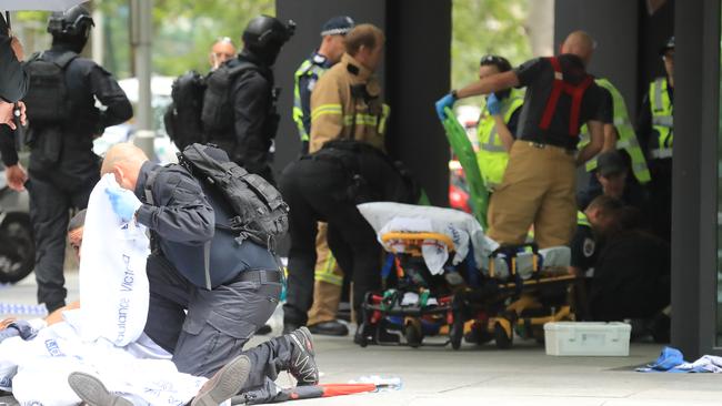 Paramedics and onlookers help the injured. Picture: Alex Coppel